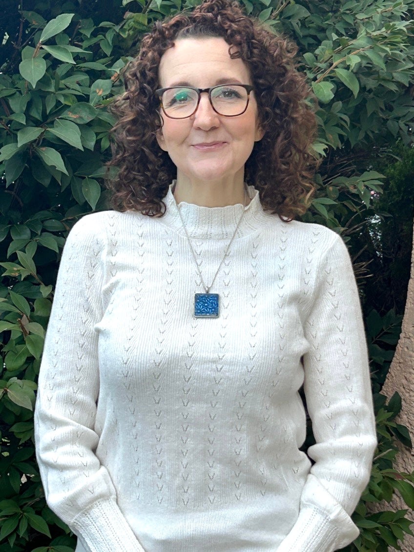 Christina standing in front of tree, with necklace on.